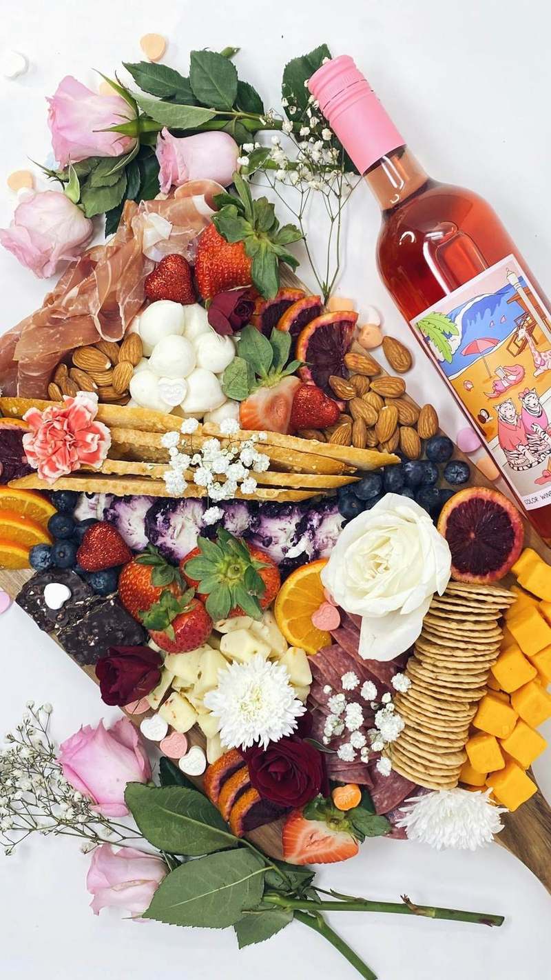 장미와 과일, 치즈, 와인이 풍성하게 차려진 그레이징 테이블